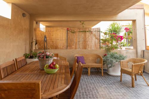 eine Veranda mit einem Holztisch, Stühlen und Blumen in der Unterkunft Case Fiorite in Riola Sardo