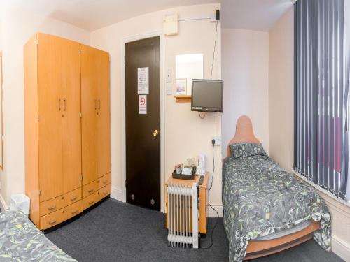 een ziekenhuiskamer met een bed en een tv bij La Tavola Calda Hotel in Nuneaton