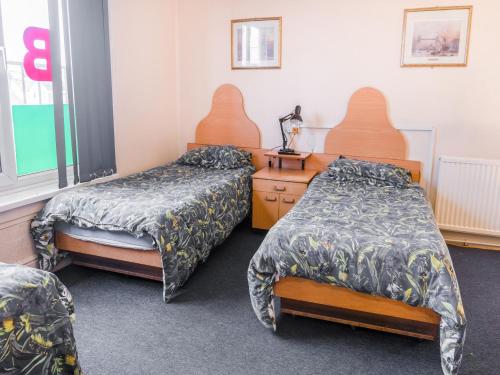 a hospital room with two beds and a dresser at La Tavola Calda Hotel in Nuneaton