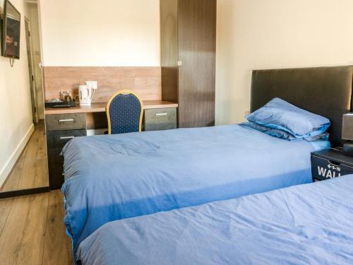 a hotel room with two beds and a desk at La Tavola Calda Hotel in Nuneaton