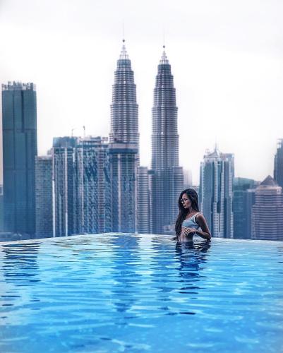 a woman sitting in a swimming pool in a city at Expressionz KLCC by Wodages, 300mbps Wifi in Kuala Lumpur