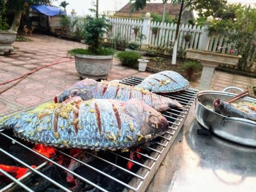 twee grote vissen koken op een grill in een tuin bij AKU HOUSE Villa Ao vua in Ba Vì