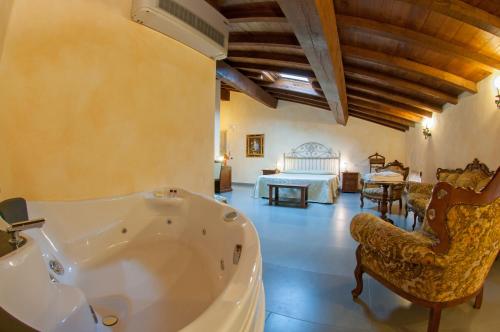 a large bathroom with a tub and a bedroom at Hotel La Tavola Rotonda in Cortemaggiore