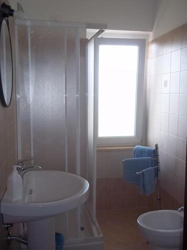 ein Badezimmer mit Waschbecken, Badewanne und Fenster in der Unterkunft Casale 920 in Agropoli