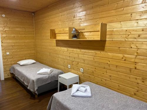 two beds in a room with wooden walls at Piejūras Kempings in Ventspils