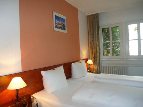 a bedroom with a bed with white sheets and a window at Hotel Burg-Stuben in Mainz