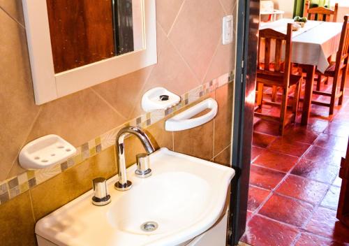 baño con lavabo y comedor en Cabañas Brisas del Cerro en Los Reartes