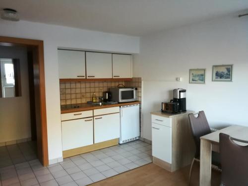 eine kleine Küche mit weißen Schränken und einer Mikrowelle in der Unterkunft Apartment Waldhaus Opitz in Zell am See