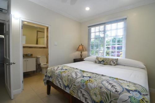 Un dormitorio con una cama grande y una ventana en Choose To Be Happy at Gardens of Blissett GOB#1 & GOB #2 - Two Bedroom Apartments en Kingston