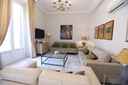 a living room with white furniture and a chandelier at Apartamento Mar de Korus in Málaga