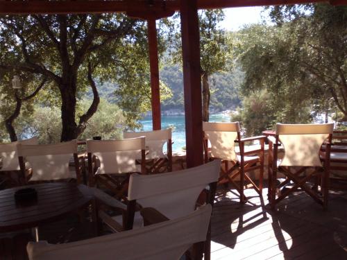 a porch with chairs and tables and a view of the water at Mikros Gialos Apartments in Mikros Gialos