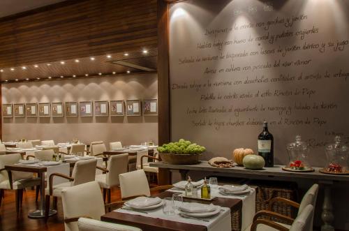 a restaurant with tables and chairs and a wall with a menu at Hotel Murcia Rincón de Pepe Affiliated by Meliá in Murcia