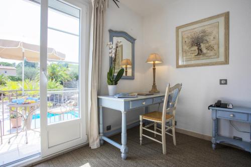 a room with a desk and a window with a balcony at La Bastide de Valbonne in Valbonne