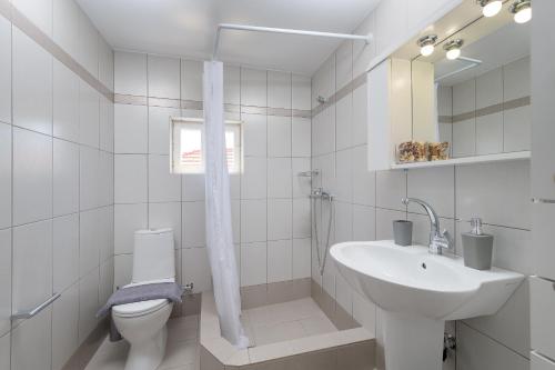 a white bathroom with a sink and a toilet at Anastasia house in Halki