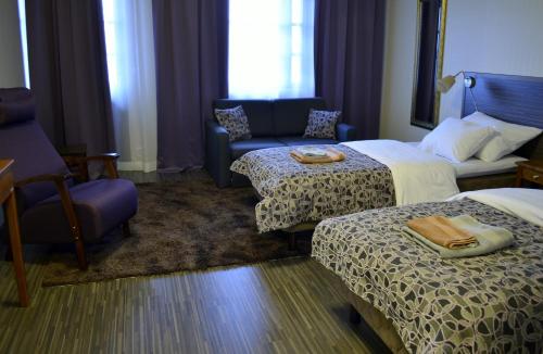 a hotel room with two beds and a chair at Kartanohotelli Saari in Reisjärvi