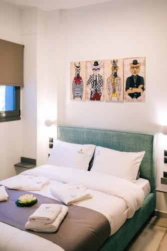 a bed in a room with two paintings on the wall at Volos Suites Center in Volos