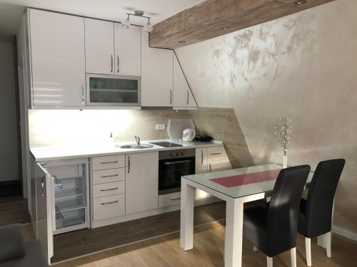une cuisine avec des placards blancs et une table avec des chaises dans l'établissement Top Kop, à Kopaonik