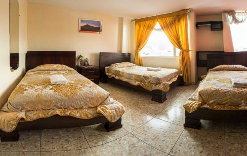 um quarto de hotel com duas camas e uma janela em Hostal La Rosa Otavalo em Otavalo