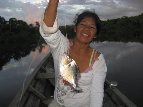 a woman holding a fish in a boat at Reserva Natural Heliconia Amazonas in Leticia