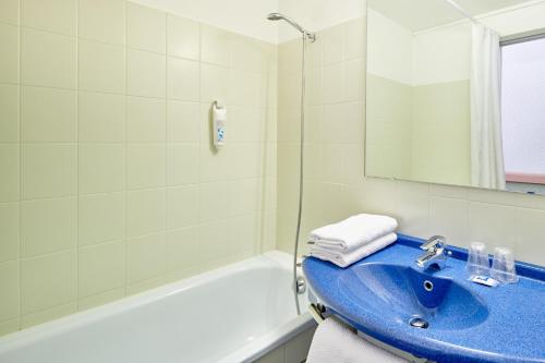 uma casa de banho com um lavatório azul e uma banheira em ibis budget Saint Paul Les Dax em Saint-Paul-lès-Dax