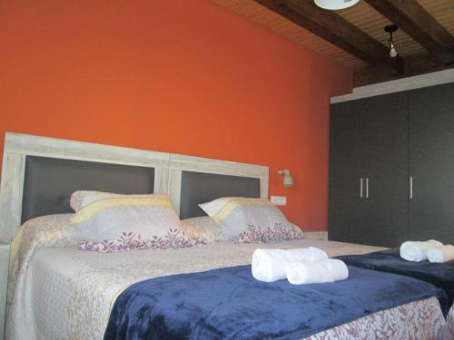two beds in a room with orange walls at APARTAMENTOS FONTE VILLAR in Navia