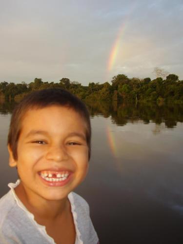 a young boy smiling with a rainbow in the background at Reserva Natural Heliconia Amazonas in Leticia