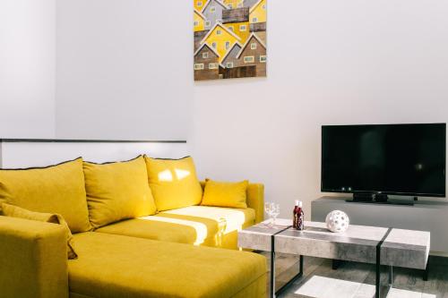 a living room with a yellow couch and a tv at Volos Suites Center in Volos