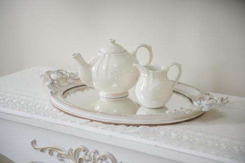 a white tea set on a plate on a table at Milcovich Suites in Barletta