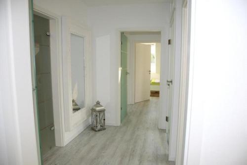 a hallway with white walls and wooden floors and a room with white walls at Zuhause Woanders - Kuhtrade in Wildeshausen