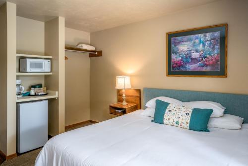 a bedroom with a white bed and a microwave at Somerset Inn & Suites in Ephraim