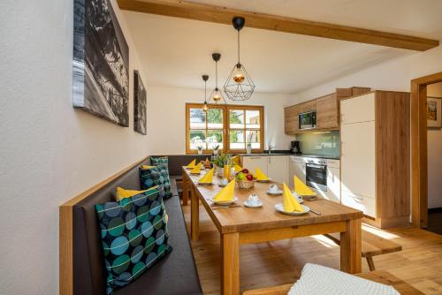 a dining room with a wooden table and a kitchen at Chalet SONNECK Summer Card included in Kaprun
