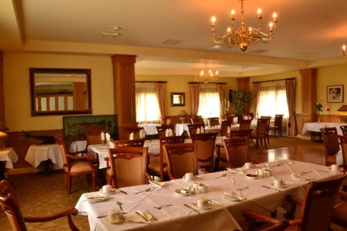 a dining room with tables and chairs and a chandelier at Fairhill House Hotel in Clonbur