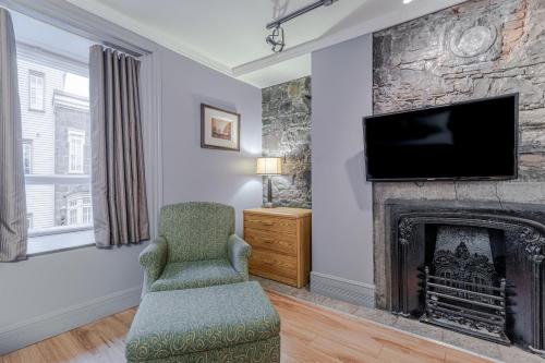 a living room with a fireplace and a tv at Hotel Jardin du Gouverneur in Quebec City