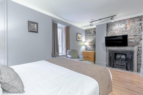 a bedroom with a bed and a fireplace at Hotel Jardin du Gouverneur in Quebec City