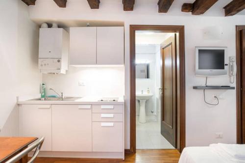 uma cozinha branca com um lavatório e uma televisão na parede em Studio in San Marco square em Veneza