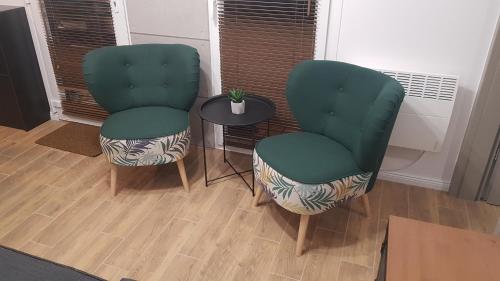 two green chairs and a table in a room at JH1 domek M&M Apartments in Altanka
