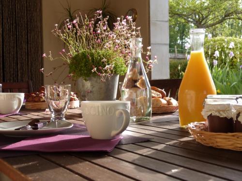 a wooden table with a table cloth and drinks on it at Chambres d'hôtes Le Cartounier in Pinel-Hauterive