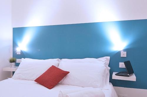 a bed with white pillows and a blue wall at Modica Old Town Rooms in Modica