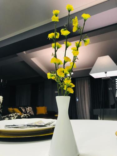 a white vase filled with yellow flowers on a table at VNVP Apartment in Štip