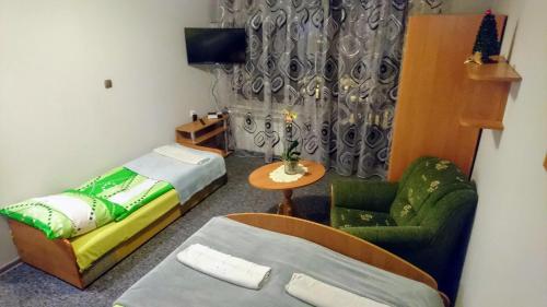 a room with two beds and a chair and a table at Apartament Frezja in Tylicz