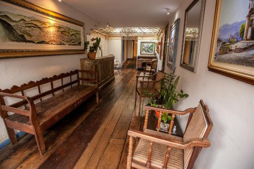 sala de estar con suelo de madera y bancos de madera en Pousada Solar da Ópera, en Ouro Preto