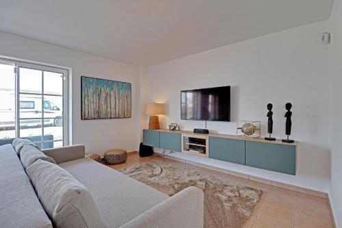 a living room with a couch and a flat screen tv at Tavira Formosa Bay 1 by Homing in Cabanas de Tavira