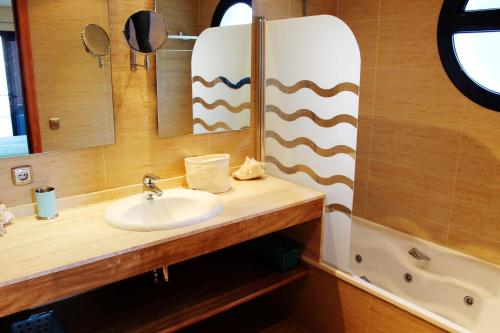 a bathroom with a sink and a mirror and a tub at Magnifica casa con jacuzzi y cerca playa ref 160 in Montjoys