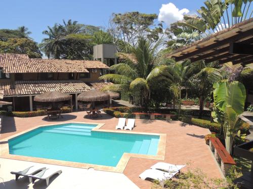 una piscina en un complejo con sillas y árboles en Marinas Pousada, en Ilhéus