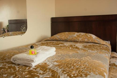 a bed with a towel and a bottle on it at Hostal La Rosa Otavalo in Otavalo