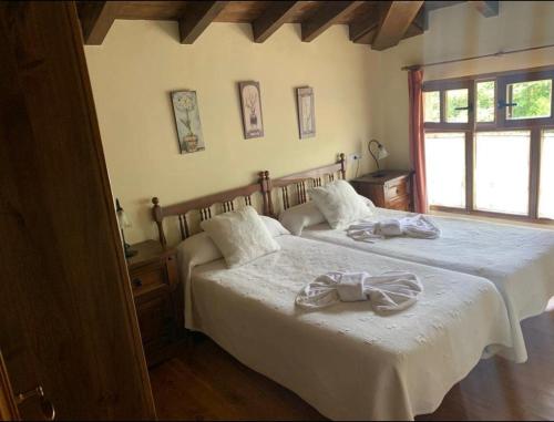 1 dormitorio con 2 camas con sábanas blancas y ventana en APARTAMENTOS MARIAJE en Barro de Llanes