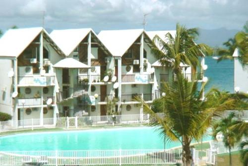 ein großes Gebäude mit einem Pool am Meer in der Unterkunft Studio spacieux en bord de mer in Le Gosier