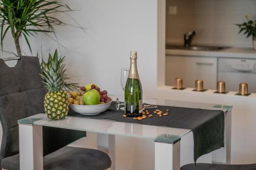 Alpha apartment في زغرب: طاولة مع وعاء من الفواكه وزجاجة من النبيذ