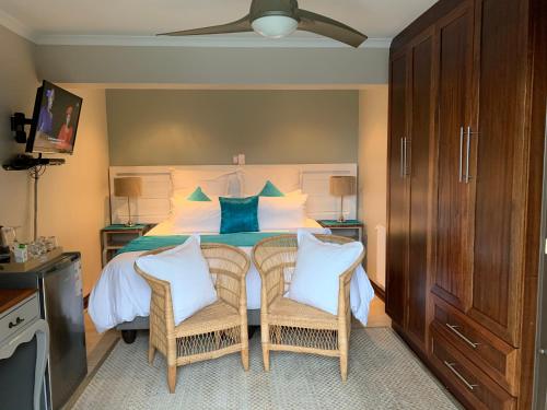 a bedroom with a bed with two wicker chairs at Bokamoso Views in Rustenburg