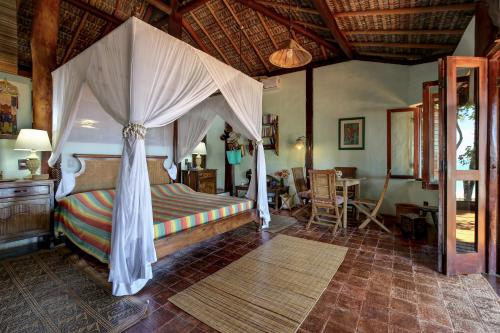 a bedroom with a bed with a canopy at Charmoso bangalô balinês pé na areia Outeiro das Brisas in Praia do Espelho